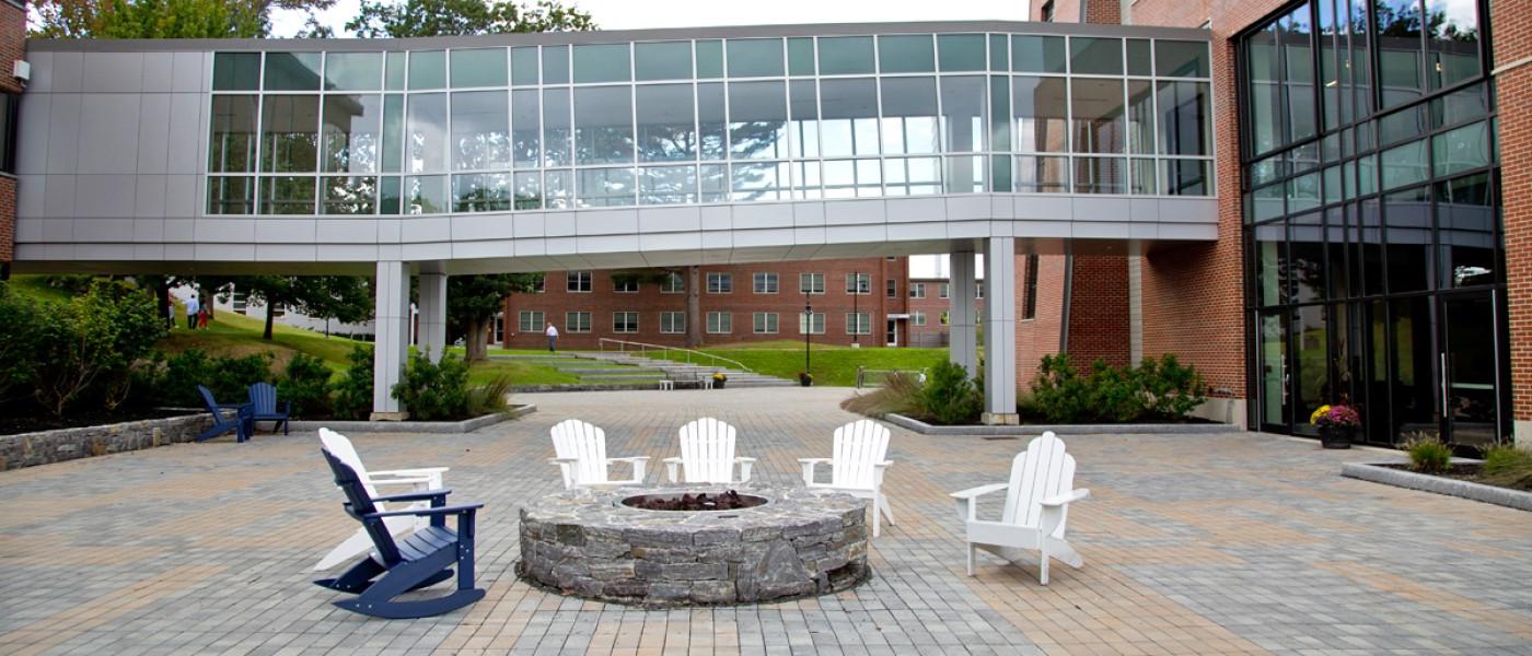 Several Adirondack chairs around a fire pit outside the Commons